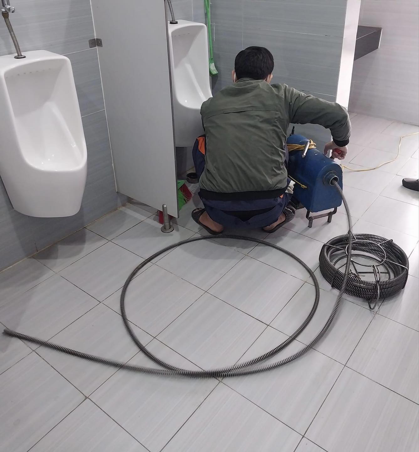 Hai kỹ thuật viên URENCO xử lý nhà vệ sinh công cộng có bồn tiểu nam tại Thạch Thất